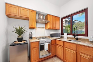 A compact kitchen with wooden cabinets, a stainless steel stove, a microwave, and a sink. - 5 BR Villa + Private Pickleball & Pool +Views (Cabo San Lucas)
