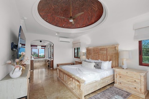 A bedroom with a wooden bed, a nightstand, a dresser, a ceiling fan, and a view of the outdoors. - 5 BR Villa + Private Pickleball & Pool +Views (Cabo San Lucas)