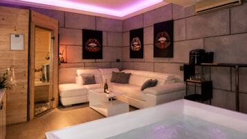 A modern spa room with a white sofa, a massage table, and a coffee machine.