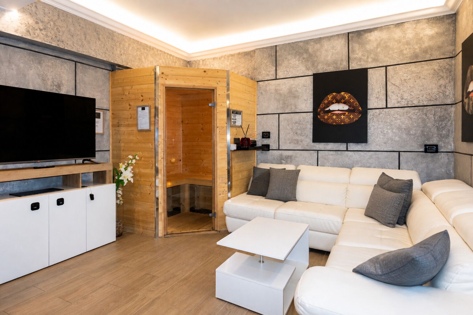 A modern living room with a white sofa, a flat-screen TV, a wooden sauna, and a stone wall with a Louis Vuitton logo.