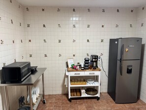 Una cocina con microondas, cafetera y refrigerador.