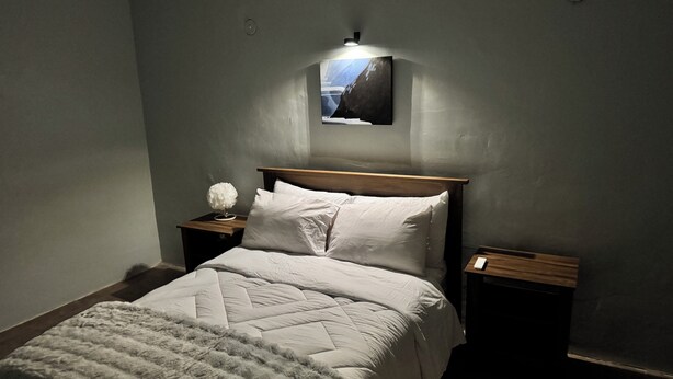 A bedroom with a bed, a nightstand, a lamp, and a wall-mounted picture. - Fantastic 2-bedroom house with AC in charming Río Blanco (Río Blanco)