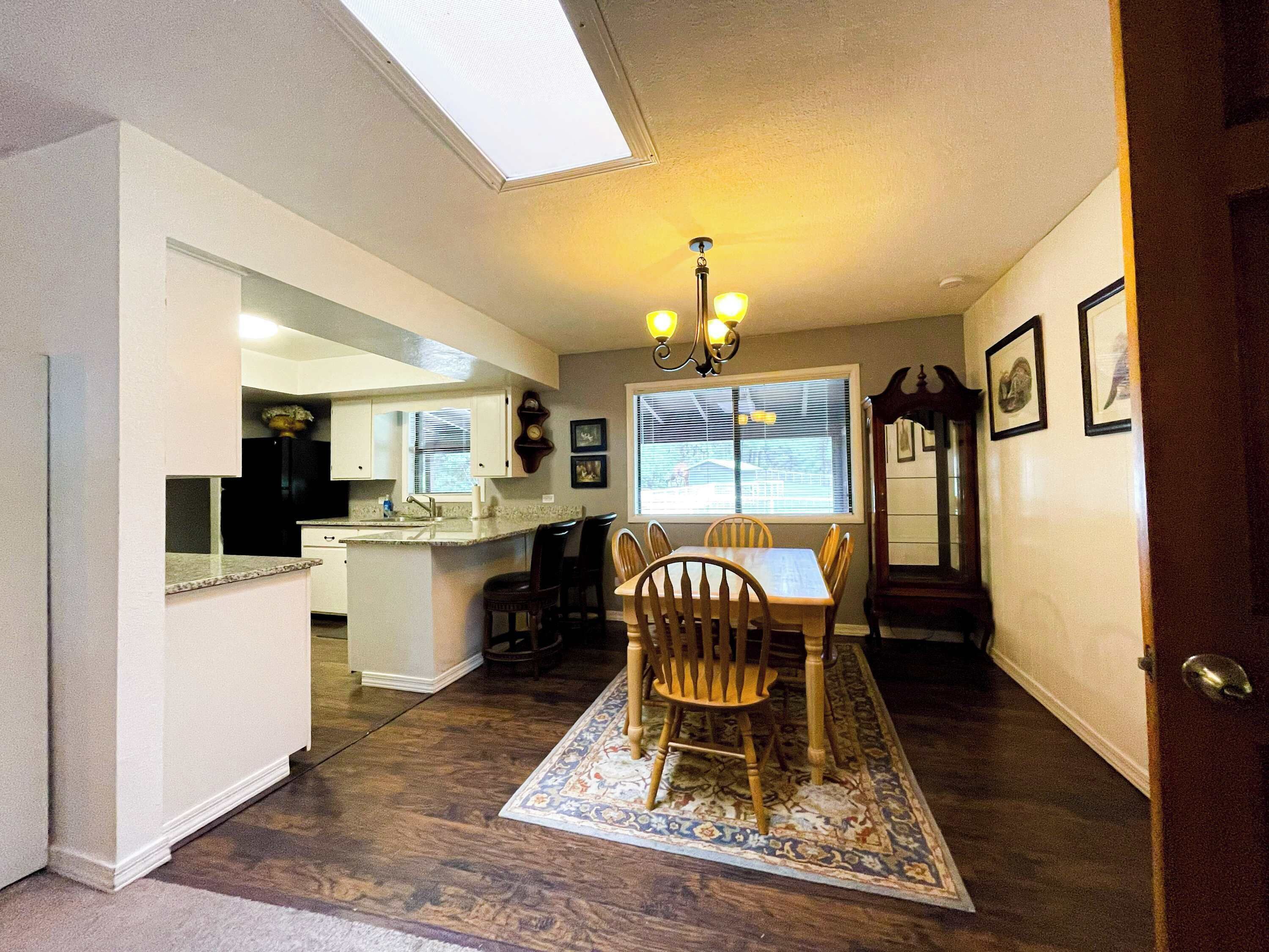 A kitchen with a dining area, a chandelier, and a window with blinds.