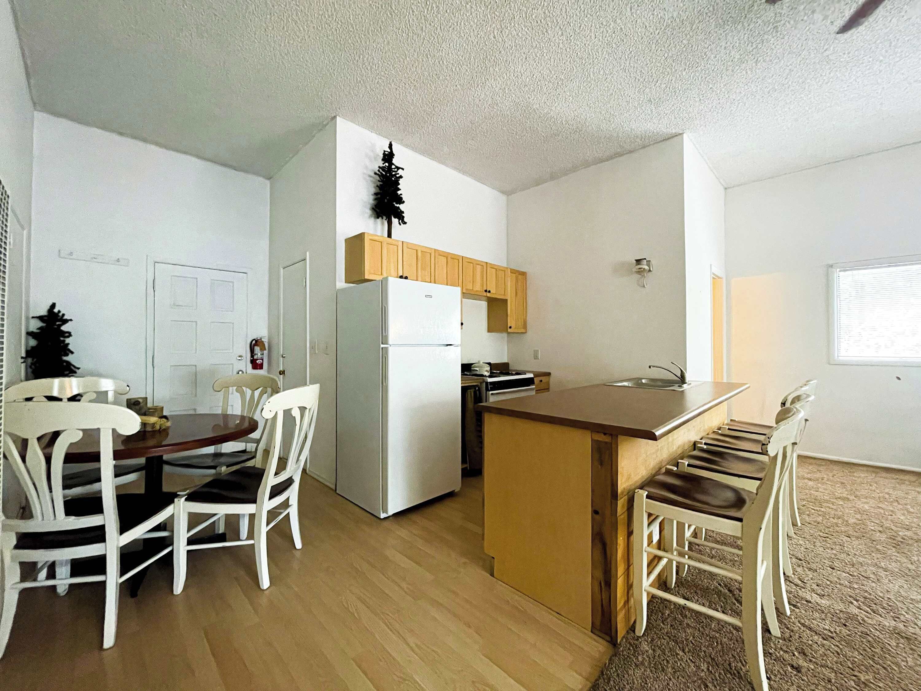 A compact kitchen with a refrigerator, stove, and wooden cabinets.