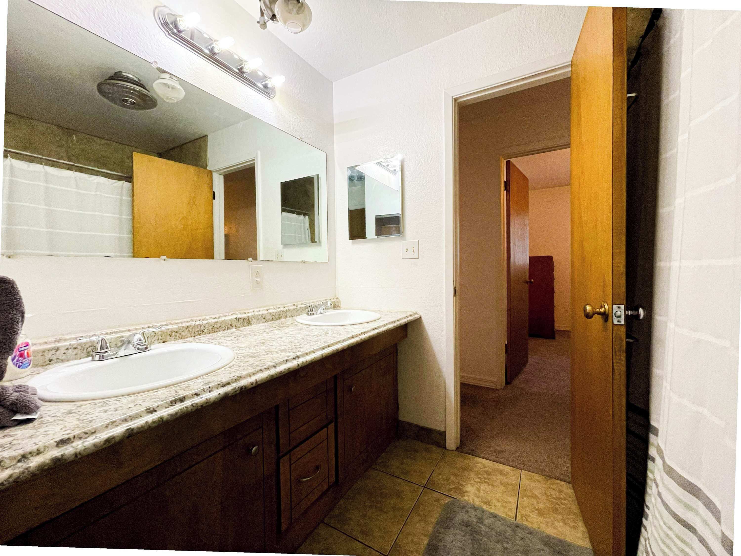 A bathroom with two sinks, a mirror, and a shower.