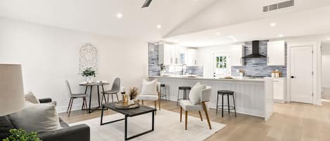 Una cocina moderna con armarios blancos, un ventilador de techo negro y una isla central con taburetes.