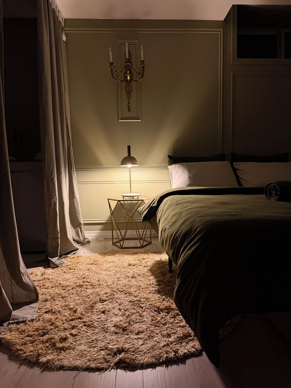 A bedroom with a bed, a nightstand, a lamp, and a candelabra.