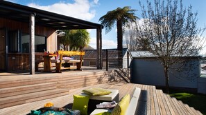 An outdoor deck with wooden flooring, a bench, and a table with chairs. - Fontaine - Stunning 4 bedroom (Daylesford)