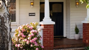 Une maison avec une porte d’entrée noire, un porche blanc et une enseigne sur laquelle on peut lire « FONTAINE ».