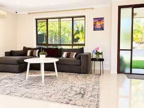 A modern living room with a grey sofa, a white coffee table, and a patterned rug. - Hilltop View & Family Comfort | Sleep                              6 (Jamboree Heights)