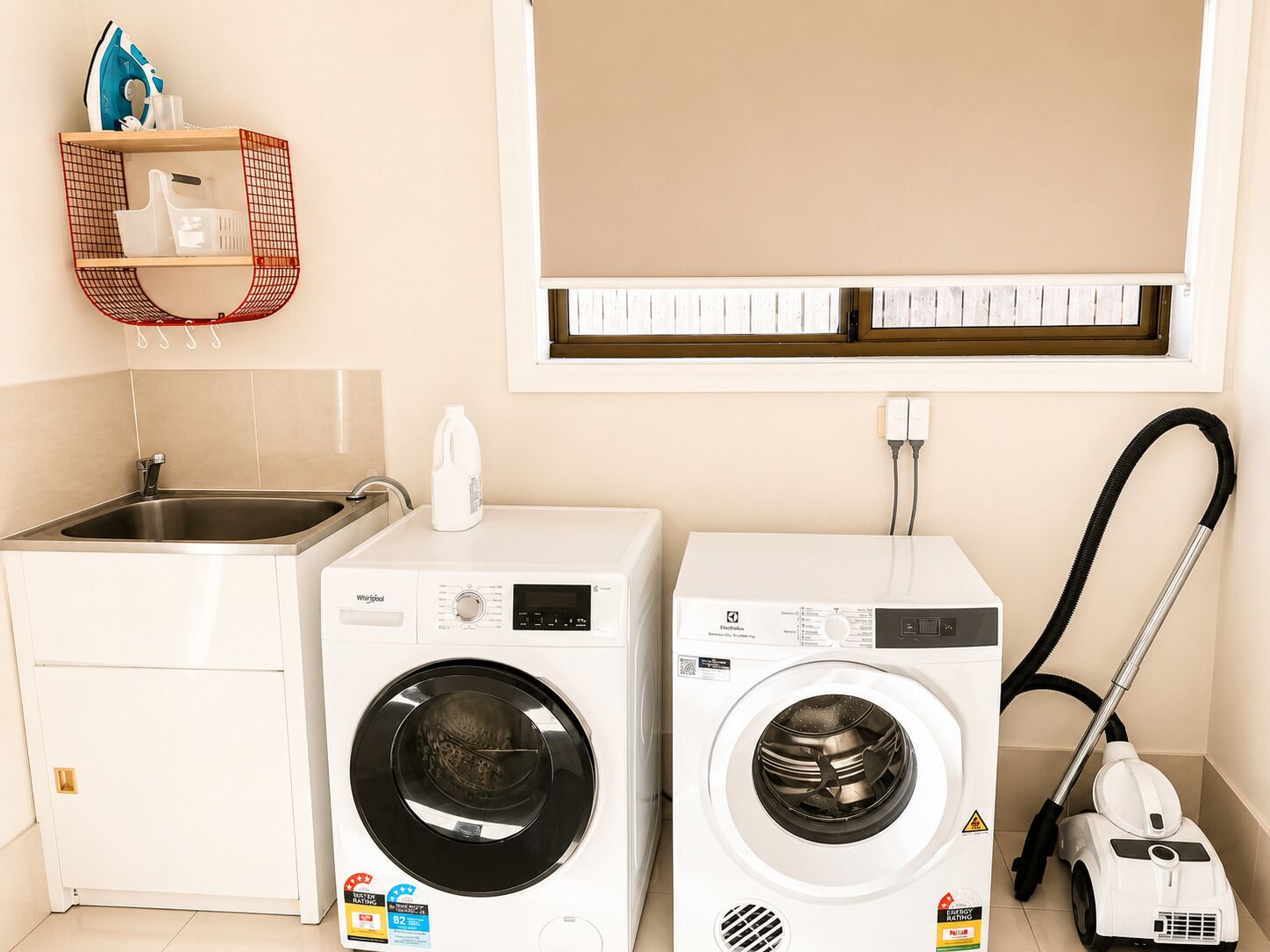 A compact laundry room with a washing machine, a dryer, and a vacuum cleaner.