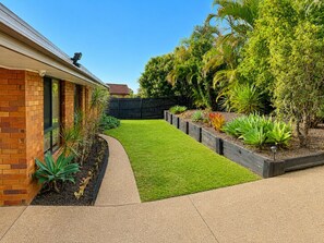 A residential backyard with a well-maintained lawn, a brick house, and various plants. - Hilltop View & Family Comfort | Sleep                              6 (Jamboree Heights)
