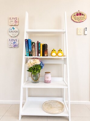 A white bookshelf with books, a vase of flowers, and a candle. - Hilltop View & Family Comfort | Sleep                              6 (Jamboree Heights)