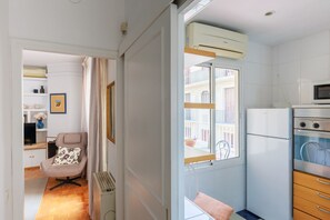 A compact kitchen with a built-in microwave, a refrigerator, and a window with a view of a balcony. - Pentahouse Banyoles, two terraces, fully furnished apartment can accommodate 2 guests (Barcelona)