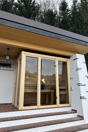 A modern building with a large glass door and wooden steps leading to a covered entrance. - Chalet Waldhüsli (CharmingStay), (Flumserberg Tannenboden), by Interhome (Flumserberg Tannenheim)