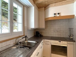 A kitchen with a double sink, a coffee maker, and a dishwasher. - Chalet Waldhüsli (CharmingStay), (Flumserberg Tannenboden), by Interhome (Flumserberg Tannenheim)