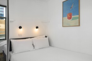 A hotel room with a bed, two wall-mounted lights, a power outlet, and a painting on the wall. - Stylish 2-Bed Apartment Near Melbourne Central (Carlton)
