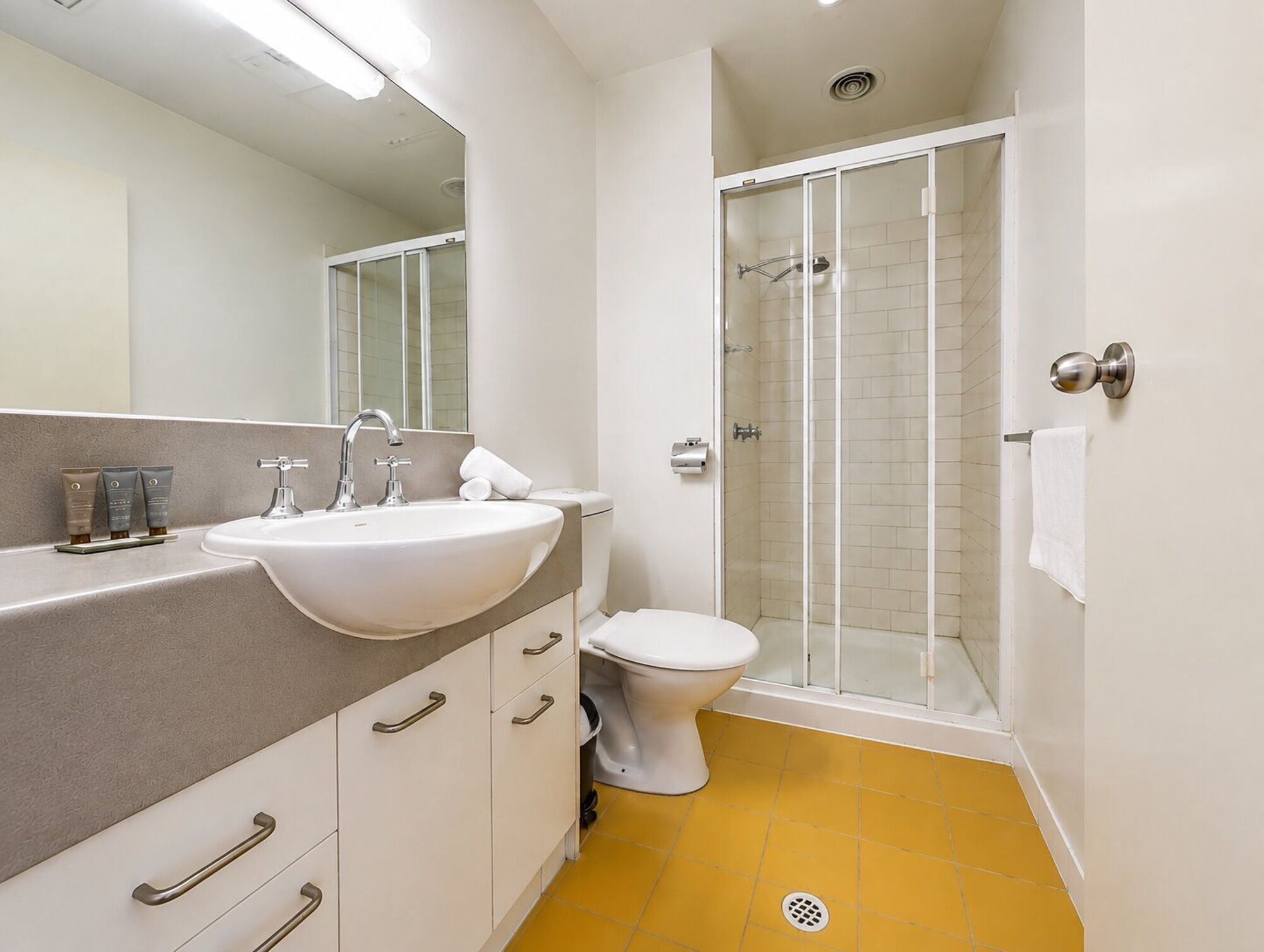 A modern bathroom with a white sink, a toilet, and a glass-enclosed shower.