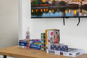 A bookshelf with travel books and jigsaw puzzles. - Stylish 2-Bed Apartment Near Melbourne Central (Carlton)