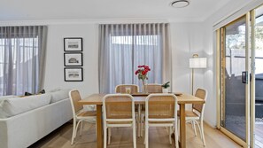 A dining area with a table, chairs, and a vase of flowers. - Nazza Daze in Narawallee (Narrawallee)