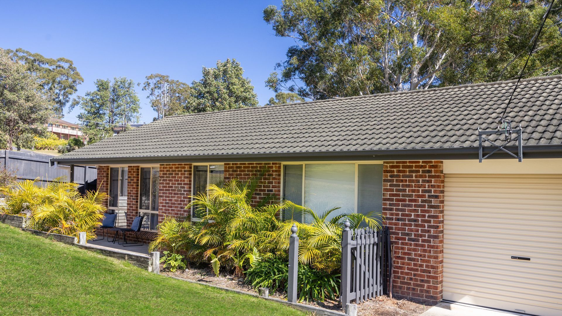 A residential house with a tiled roof, brick walls, and a garage door.