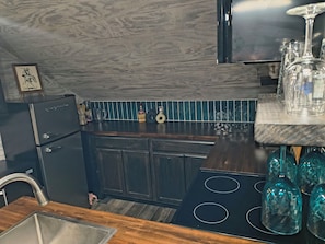 A kitchen with dark wooden cabinets, a stainless steel sink, and a black stove.