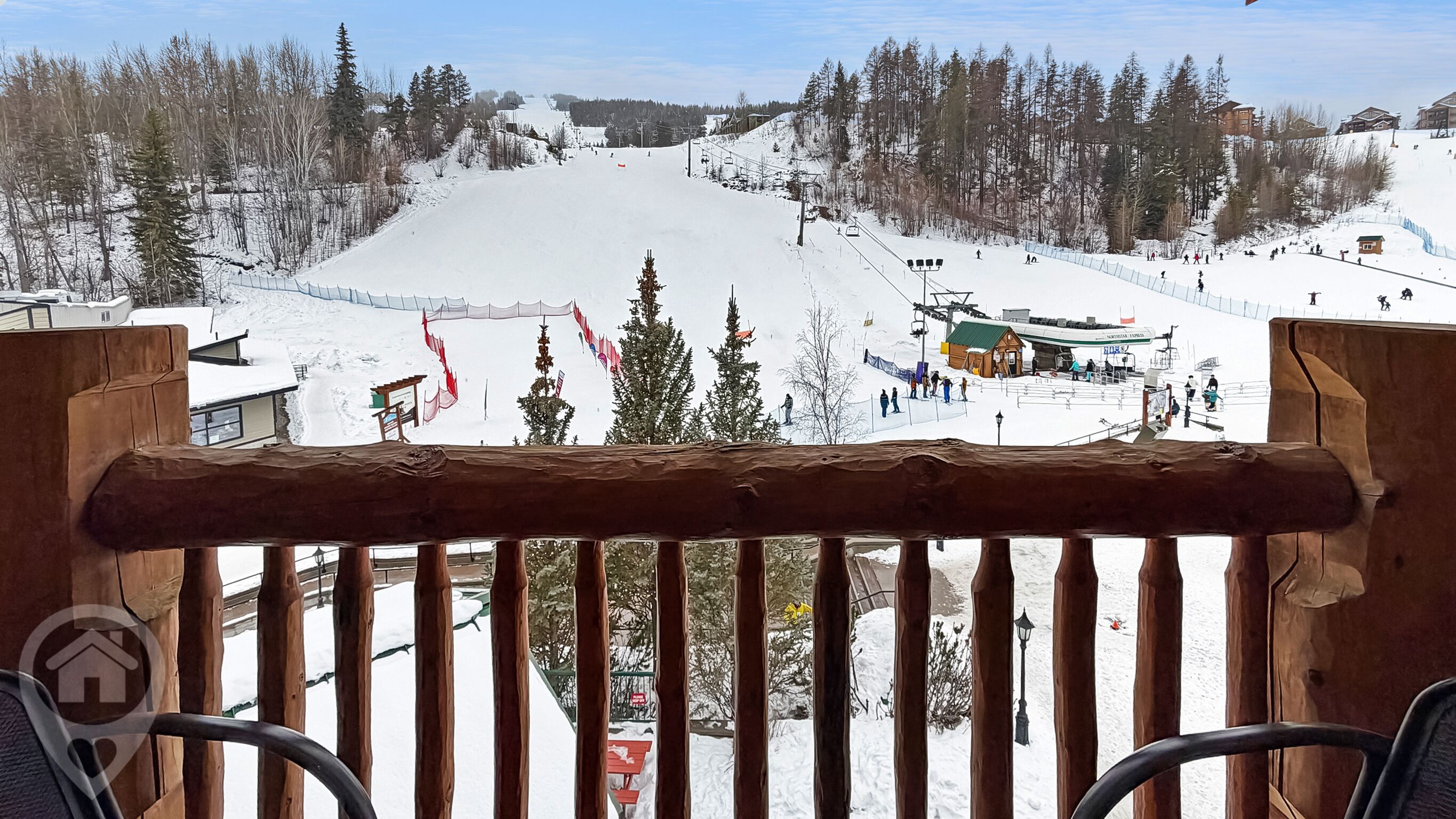 Une piste de ski enneigée, avec une clôture en bois au premier plan.