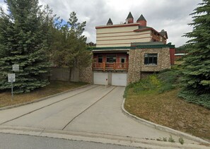 Un bâtiment doté d’une façade en pierre, d’un balcon en bois et d’une porte de garage.