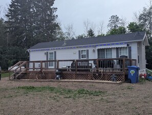 A two-story house with a porch, a wooden fence, and a recycling bin.