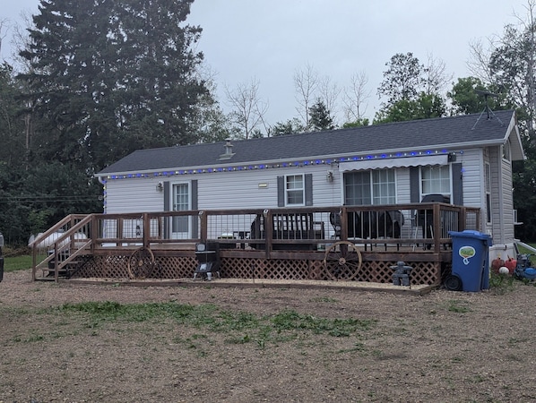 Une maison à deux étages avec un porche, une clôture en bois et un bac de recyclage.