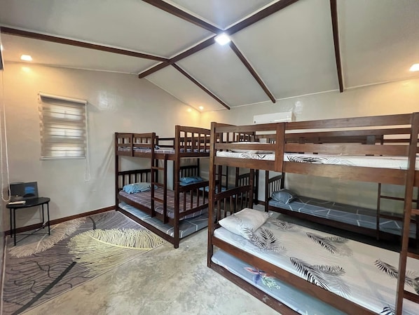 Une chambre de dortoir avec des lits superposés, une petite table et une fenêtre avec des stores.