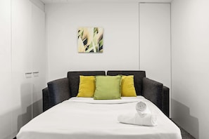 Ein Hotelzimmer mit Bett, Kissen, Handtuch und einem Gemälde an der Wand.
