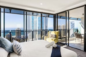 Ein Hotelzimmer mit einem großen Bett, einem gelben Sessel und einem Balkon mit Blick auf die Stadt.