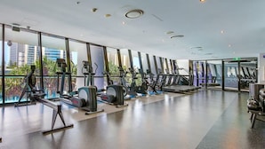 Ett modernt gym med konditionsmaskiner, en viktbänk och stora fönster med utsikt över staden.