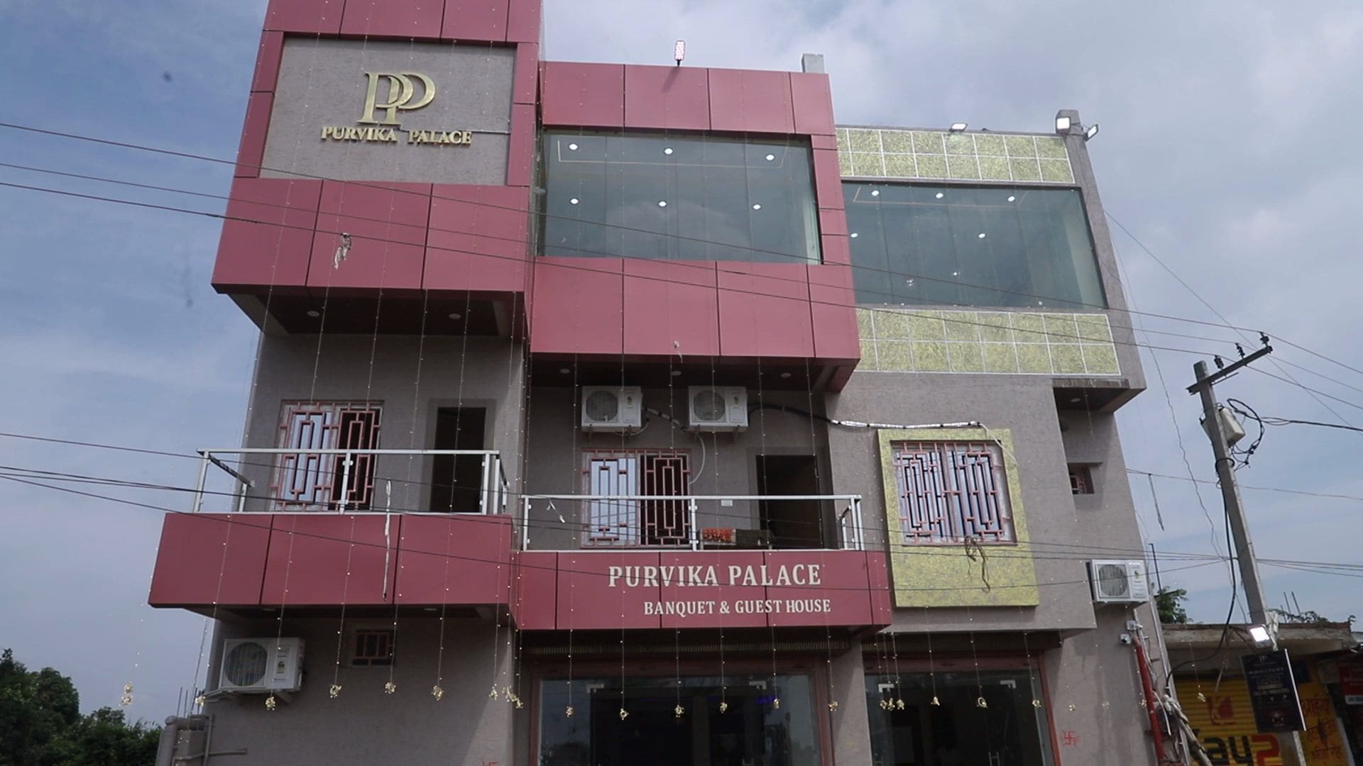 Un edificio de varios pisos con señalización que indica 'Purvika Palace Banquet & Guest House'.