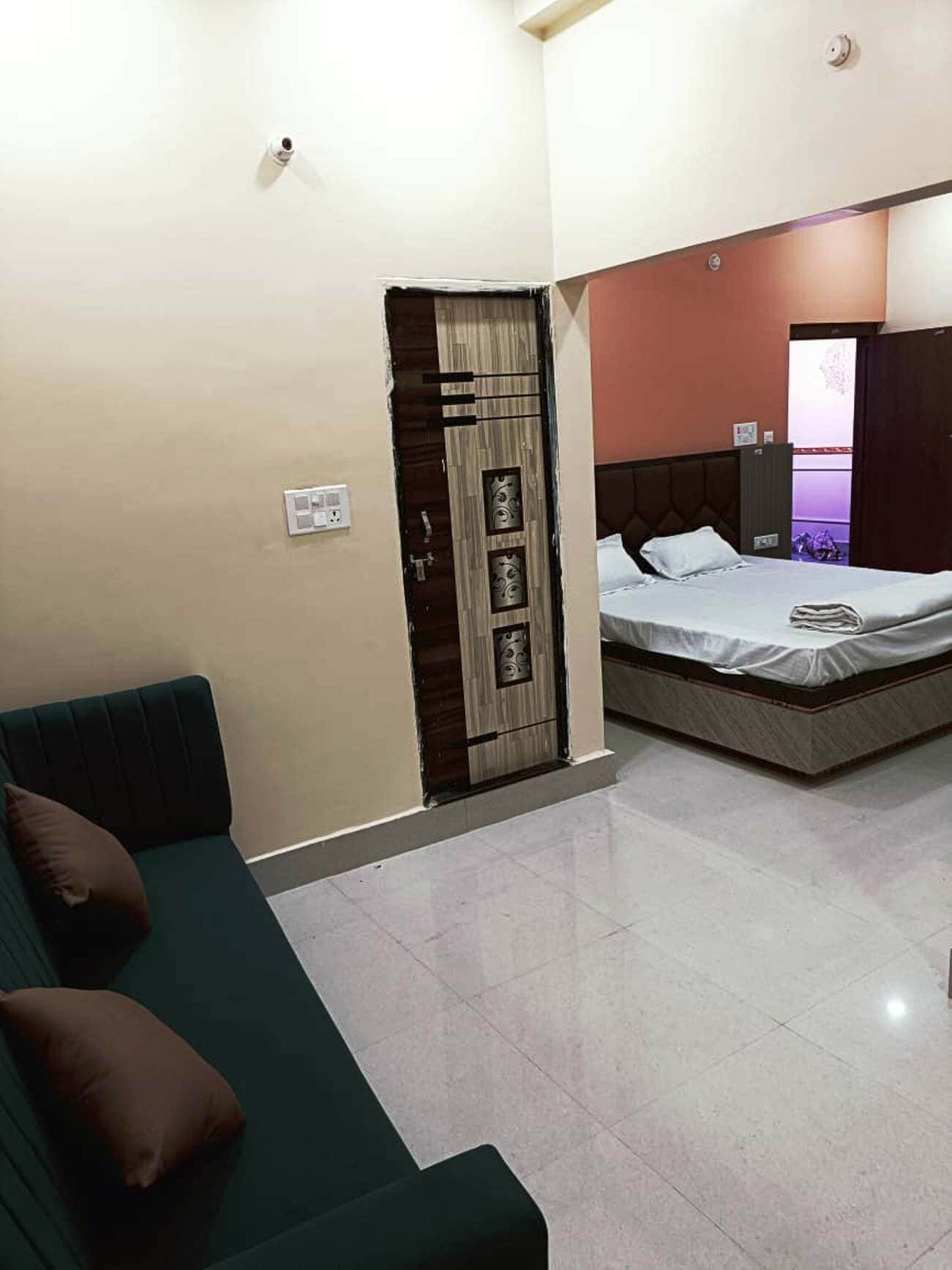 Quarto com cama, guarda-roupa e sofá verde.