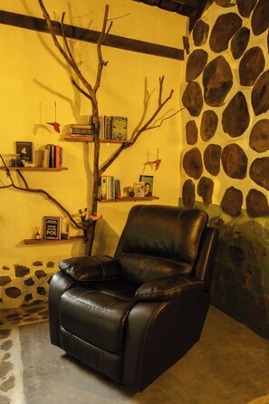 A black leather chair in a room with a stone wall and a bookshelf.