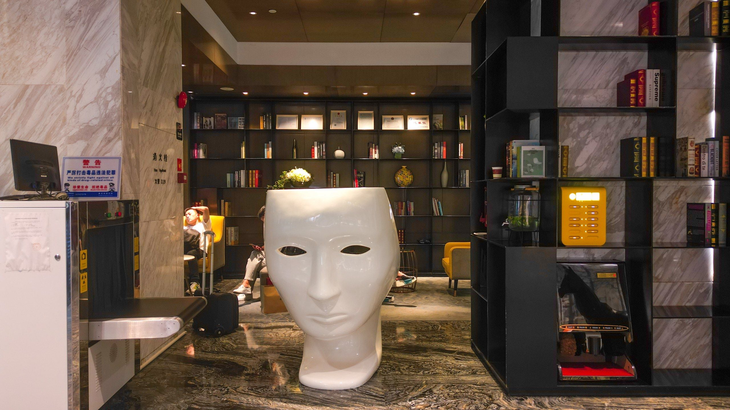 A lobby with a large white sculpture, a reception desk, and a bookshelf filled with books.