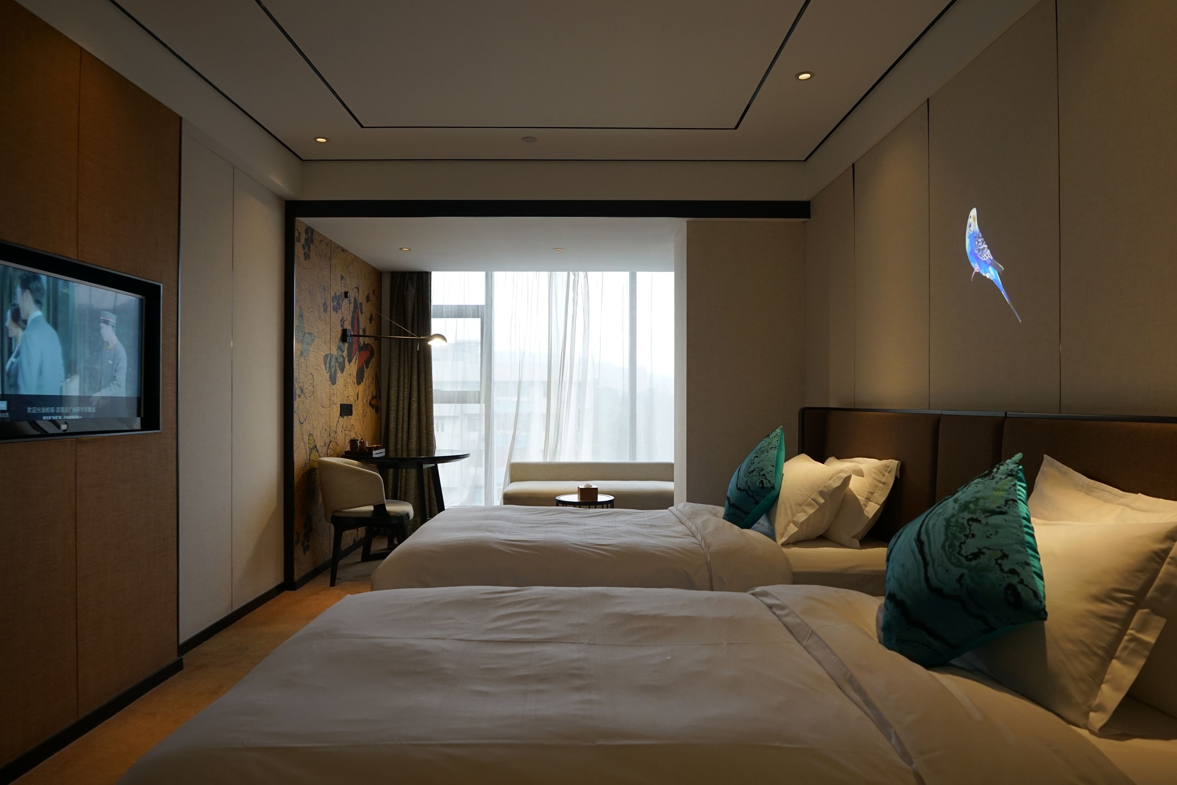 A hotel room with two beds, a television, a desk, and a large window.
