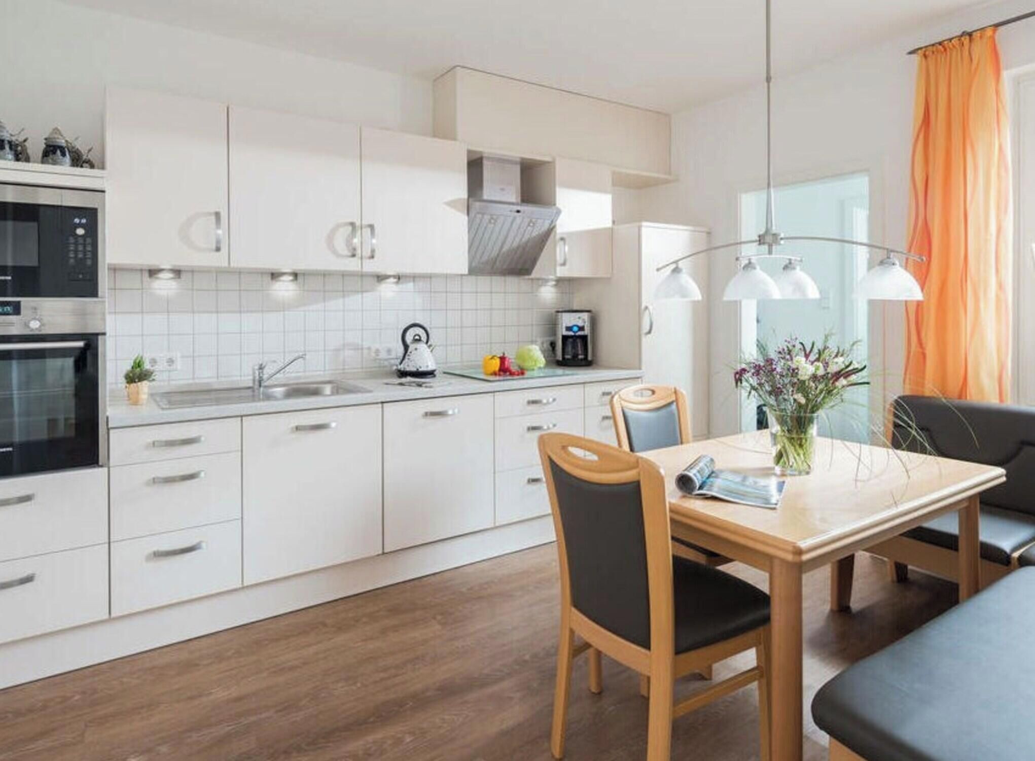 A modern kitchen with white cabinetry, a built-in oven, and a coffee machine.