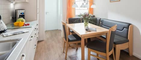 Une cuisine compacte avec un coin repas, comprenant une table en bois, des chaises et un banc en cuir noir.