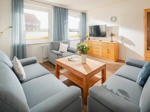 A modern living room with two sofas, a wooden coffee table, a television, and a cabinet. - Haus Schmalenbeck Lucius 2 (Norderney)