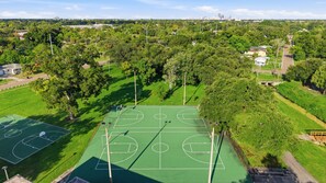 Ein Basketballplatz, umgeben von Bäumen, mit einer Stadtkulisse im Hintergrund.