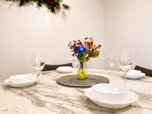 A dining table with white plates, clear wine glasses, and a vase with colorful flowers. - 1Bed 1Bath Ground floor West End (West End)