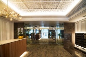 A hotel lobby with a marble floor, a reception desk, a chandelier, and a glass wall leading to the entrance. - Stylish Potts Point Apartment | Walk to Kings Cross (City of Sydney)