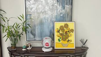 Una consola de madera oscura con objetos decorativos, un cuadro abstracto enmarcado y una planta en maceta.