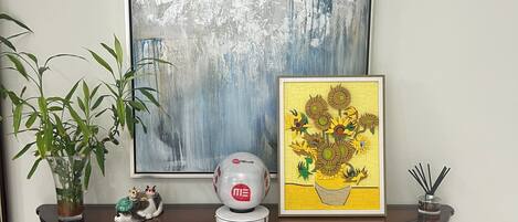 A dark wooden console table with decorative items, a framed abstract painting, and a potted plant.