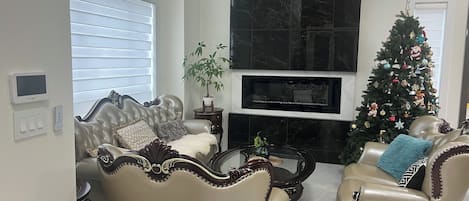 A living room with two leather armchairs, a coffee table, a fireplace, and a Christmas tree.