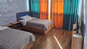 Un dormitorio con dos camas, piso de madera y cortinas con motivos forestales.