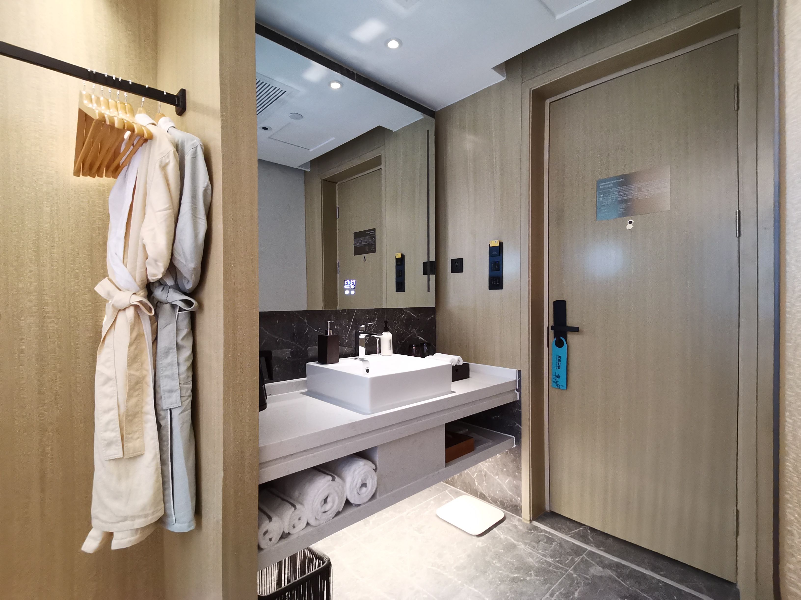A modern bathroom with a large mirror, a sink, and a towel rack.